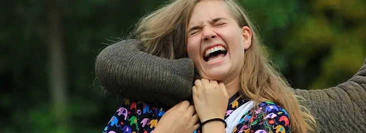 woman laughing playing with elephant close up