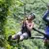 young woman and man ziplining through forest