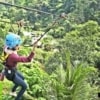 young woman ziplining through forest