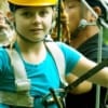 young girl preparing to zipline through jungle
