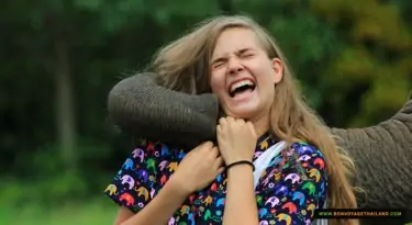 close up of young woman laughing and playing with elephant