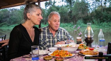 man and woman enjoying traditional thai dinner on ping river cruise