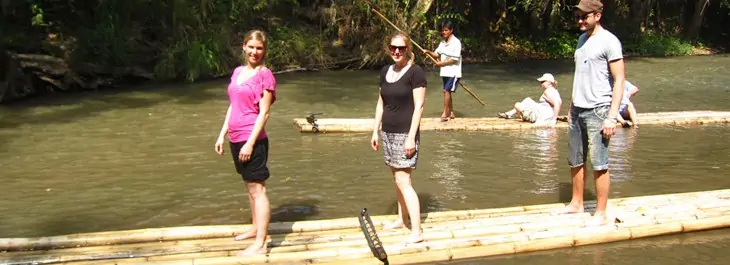group of people bamboo rafting along mae wang river