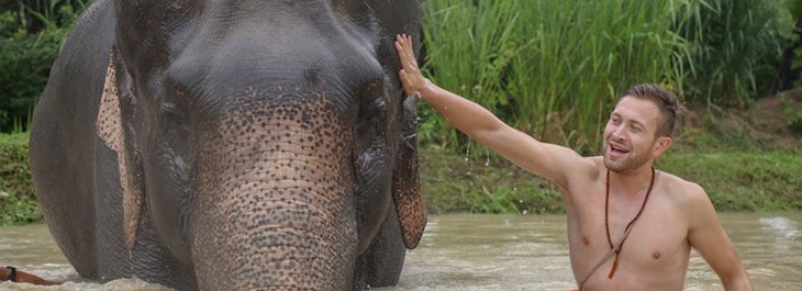 young man giving elephant a bath in river