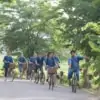 group of people cycling along rice paddy in the country