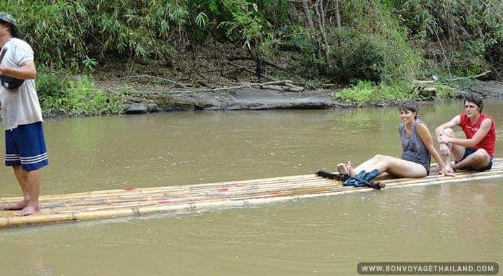 young man and woman bamboo rafting along local river