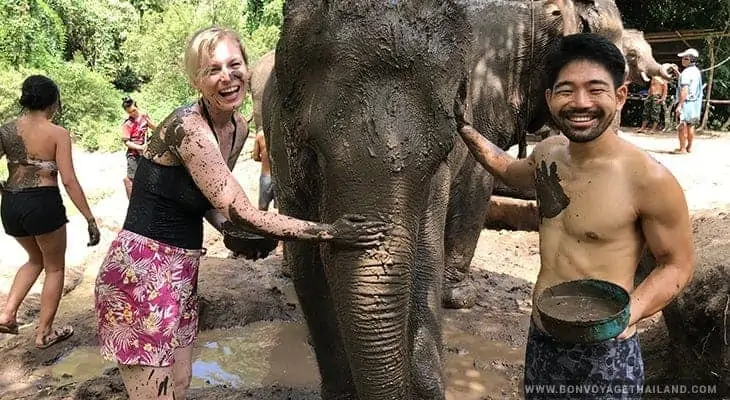 happy young couple giving elephant mud spa