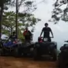 group of people posing for photo with atv on top of mountain