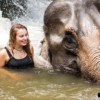 young woman swimming with elephant in waterfall
