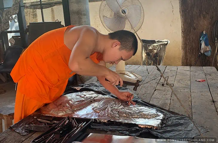 Monk working on a silver panel